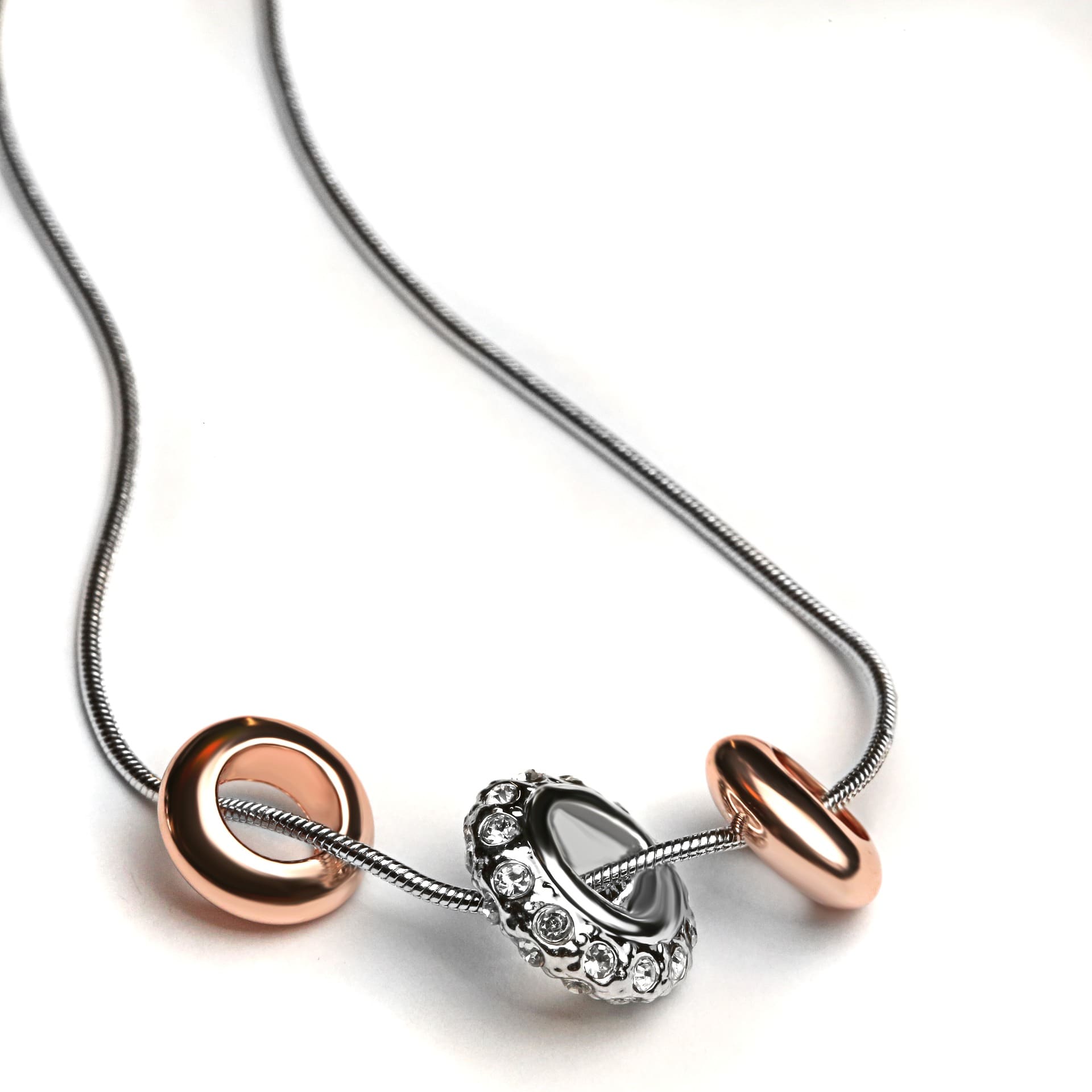 Zilveren slangenketting met roségouden ringen en een met steentjes bezette bedel